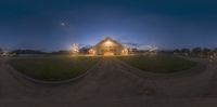 the church is surrounded by bright lights and grass in front of it, at night