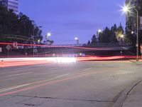 an empty road and some tall buildings with lights at night time outside on a street