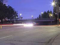 an empty road and some tall buildings with lights at night time outside on a street