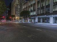 a city street is empty with no traffic at night, so the buildings are illuminated up