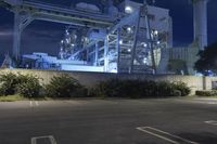 an industrial power plant with lights lit on the side of it at night time - the sky is clear