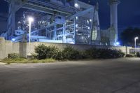 an industrial power plant with lights lit on the side of it at night time - the sky is clear