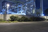 an industrial power plant with lights lit on the side of it at night time - the sky is clear