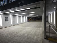 the entrance of an empty parking garage with multiple signs above it and a staircase leading to the basement