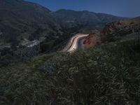 a winding road and a hillside at night with lights on the sides of the hills