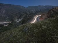 a winding road and a hillside at night with lights on the sides of the hills