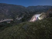 a winding road and a hillside at night with lights on the sides of the hills