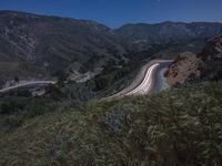 a winding road and a hillside at night with lights on the sides of the hills