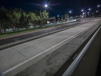 an empty road on a windy night in the country of california, with lights above