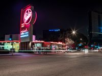 an empty street with signs on the front and back of it at night near some buildings