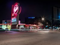 an empty street with signs on the front and back of it at night near some buildings