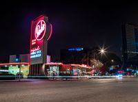 an empty street with signs on the front and back of it at night near some buildings