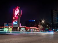 an empty street with signs on the front and back of it at night near some buildings