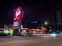 an empty street with signs on the front and back of it at night near some buildings