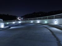 a person on a skateboard performs stunts on a bridge in the dark night with lights on