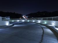 a person on a skateboard performs stunts on a bridge in the dark night with lights on