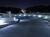 a person on a skateboard performs stunts on a bridge in the dark night with lights on