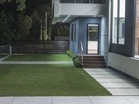 an outdoor lawn at night with lighting and artificial grass on the walkways and steps to the side