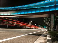 red traffic lights streaks over a city street at night, with an underpass passing over the road