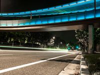 red traffic lights streaks over a city street at night, with an underpass passing over the road