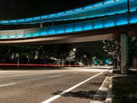 red traffic lights streaks over a city street at night, with an underpass passing over the road