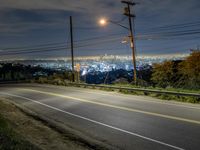 an empty road at night, with some lights shining on the horizon in the background