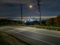 an empty road at night, with some lights shining on the horizon in the background