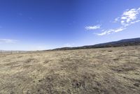 the vast dry prairie sits empty in a sunny day with a few clouds in the sky