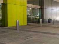 a large empty building with a yellow and green door in the middle of it by a street