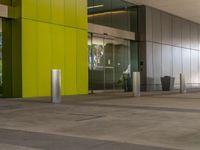 a large empty building with a yellow and green door in the middle of it by a street