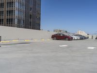 two cars sit in an empty parking lot, surrounded by building facades in a city