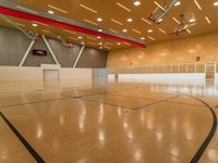 a wooden court with black and red lines and basketball hoops on the bottom of it