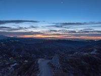 an elevated view of the mountains and valley at dusk with a street in the distance