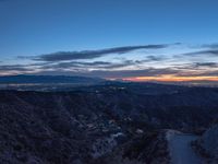 an elevated view of the mountains and valley at dusk with a street in the distance