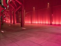 the red interior of a building that is lit up in pink color with a large pipe