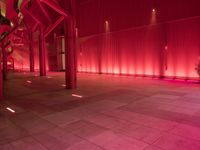 the red interior of a building that is lit up in pink color with a large pipe