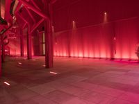 the red interior of a building that is lit up in pink color with a large pipe