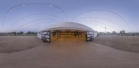 a large open tent with a covered outdoor space with multiple lights in front of it