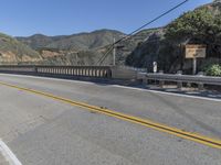 a bridge and traffic signal are on the street in the mountainsidess of california