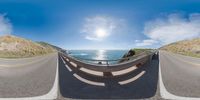 a fish eye lens photo of the highway overlooking the ocean and mountains with sea view