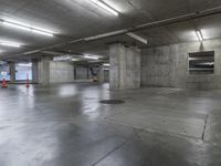 empty parking garage with lots of empty concrete walls and large cement floors, with lots of empty spaces on the left