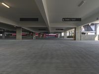 a parking garage with cement floors and large ceilings with signs at one end of the parking space