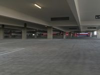 a parking garage with cement floors and large ceilings with signs at one end of the parking space