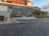 a parking lot with two cones and a parking meter on one of the sides of the buildings