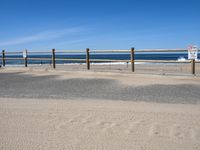 a paved beach with a fence in front of it and the ocean in the distance