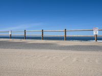 a paved beach with a fence in front of it and the ocean in the distance