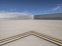 a yellow strip lines on an empty concrete floor in a parking lot where parked cars are behind the wall