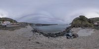 a pier sitting in the middle of a rocky ocean shore filled with boats on a clear day