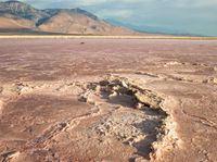 the vast expanse is covered by very pink rocks and sand the mountains appear to be in the distance