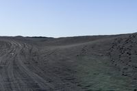 a dirt road curves into a dry, flat, barren land at dusk time in a remote location